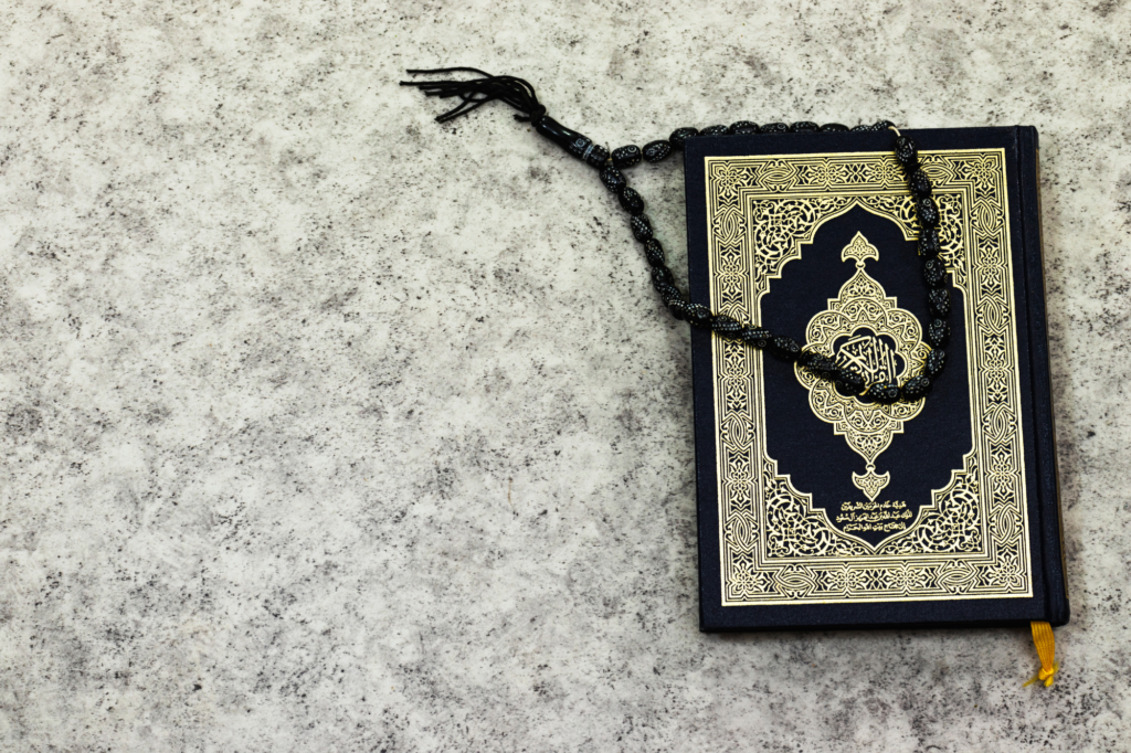 A picture of an Islamic spiritual book with a black prayer bead bracelet on top