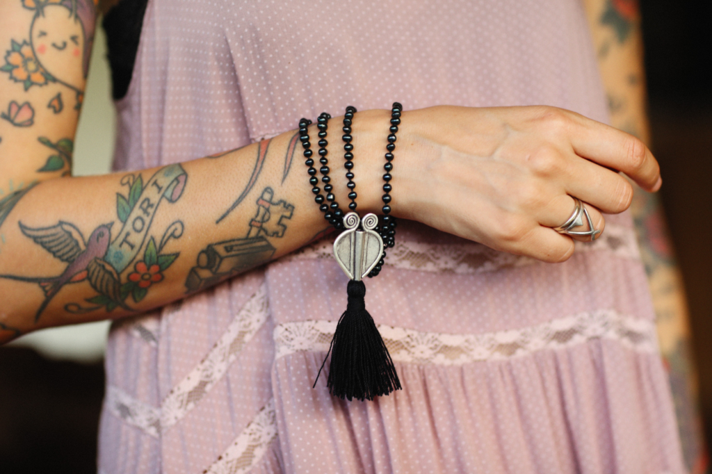 A picture of a woman wearing black mala beads on her wrist